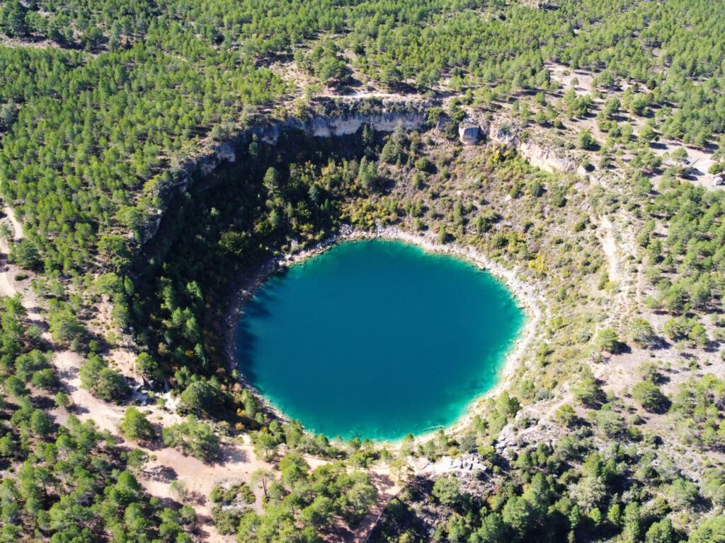 Vista aérea de una de las lagunas de Cañada del Hoyo rodeada de pinar, Cuenca