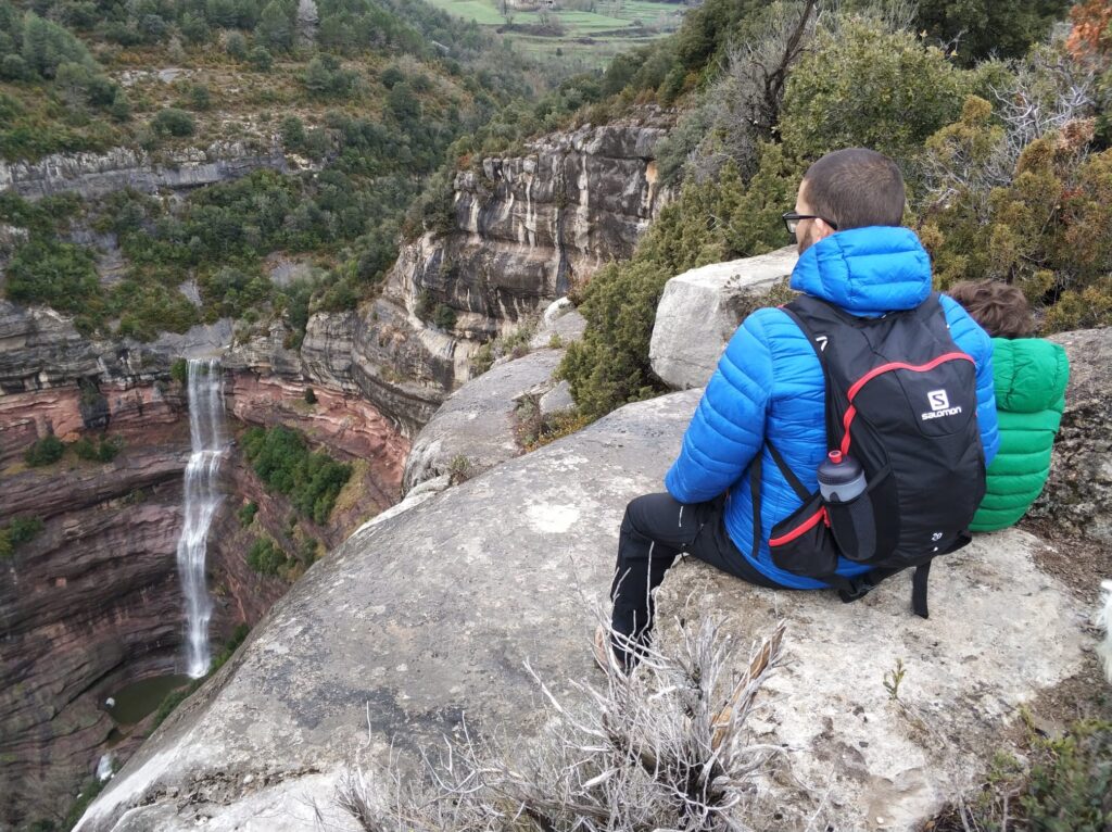 adre e hijo sentados contemplando una cascada en ruta familiar