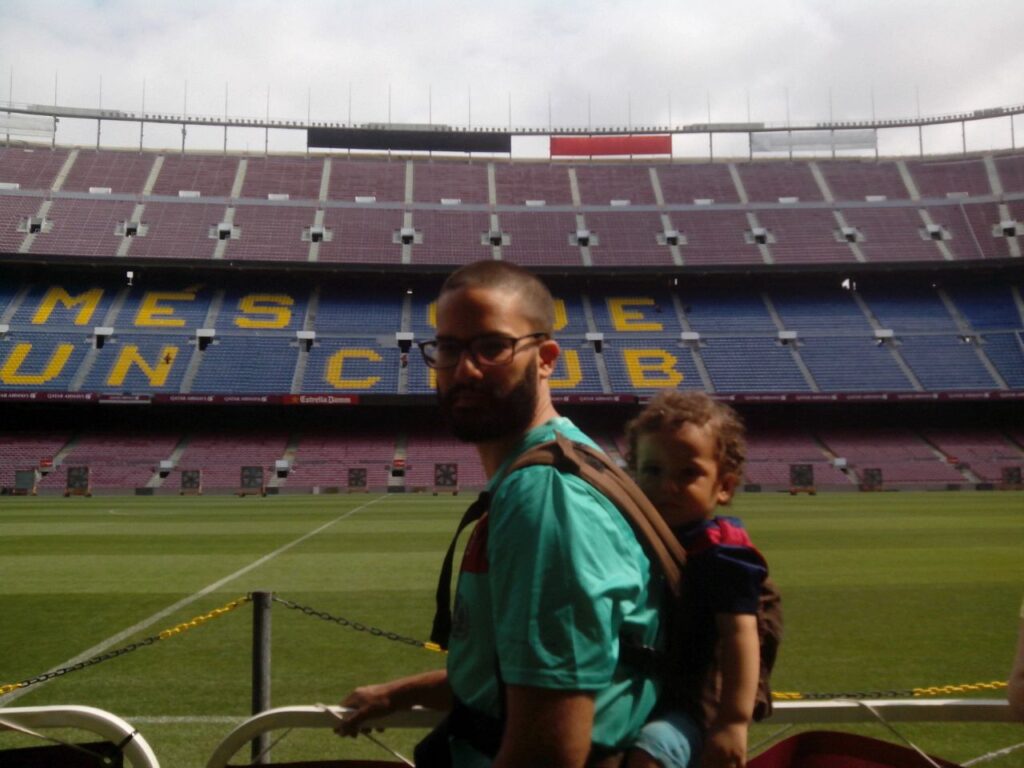padre con mochila portabebes porteando a su hijo en el Camp Nou, Barcelona