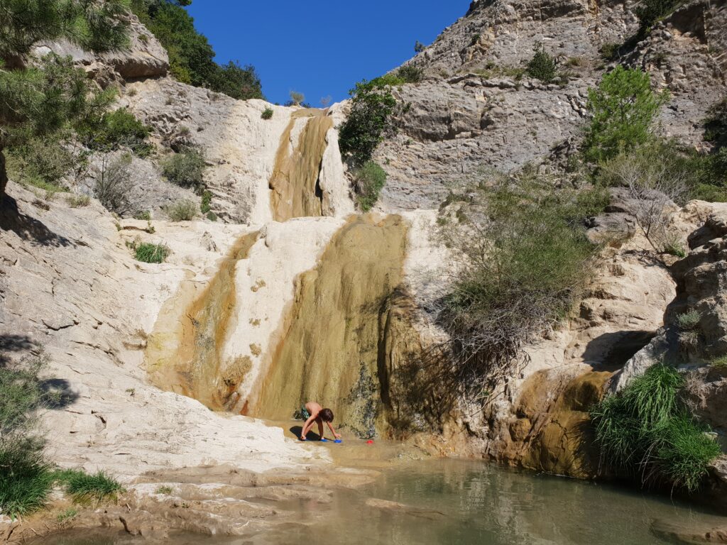 Niño jugando en la poza natural bajo la cascada de Organyà
